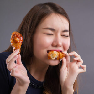 hungry asian woman eating fried chicken