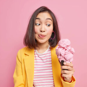 pretty young dark haired asian woman looks appetizing yummy ice cream licks lips with tongue cannot wait until eating delicious summer dessert dressed fashionable clothes sweet tooth concept (1)
