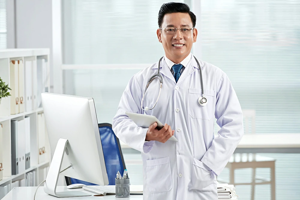 confident doctor looking camera holding tablet pc