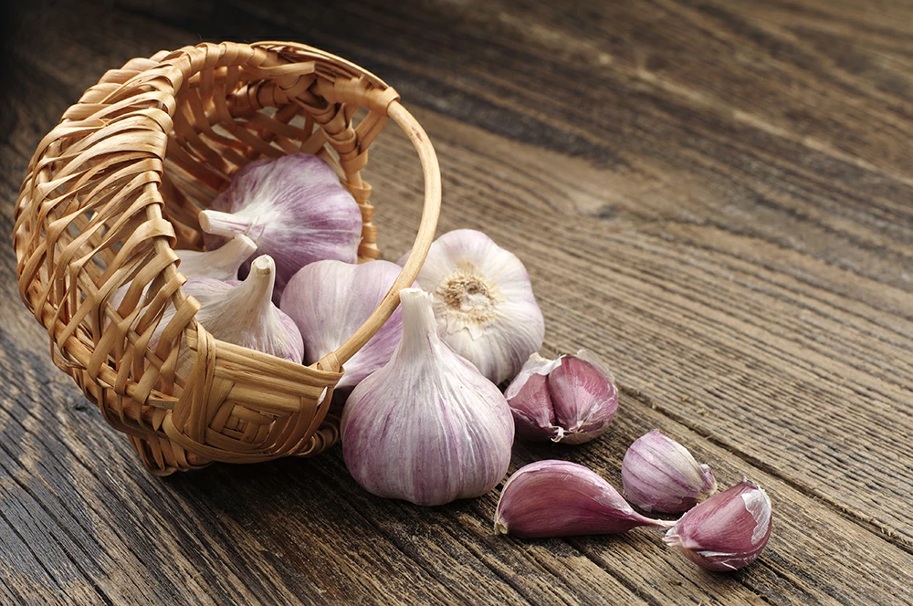 garlic wicker basket near wooden table