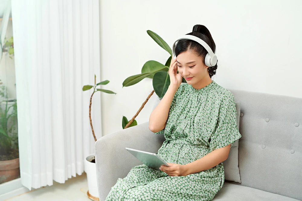 smiling beautiful asian listening music while using her tablet living room